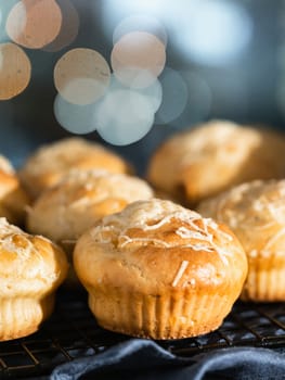 Delicious savory salted muffins with cream cheese, herbs and spices, topping grated parmesan. Cozy autumn winter pastries with festive bokeh background. Copy space for text or design. Vertical