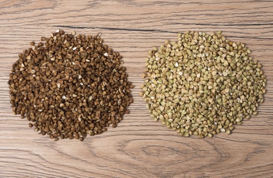 Pile of buckwheat and green buckwheat on wooden background. Top view.