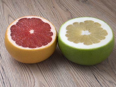 Halves of Green Sweetie and Red Grapefruit on wooden background. Close up view.