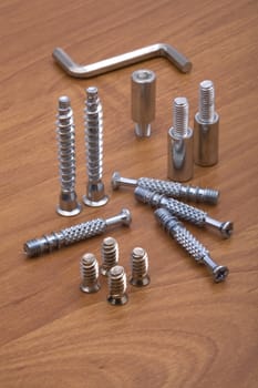 Set of modern bolts and screws for furniture assemblage on wooden table