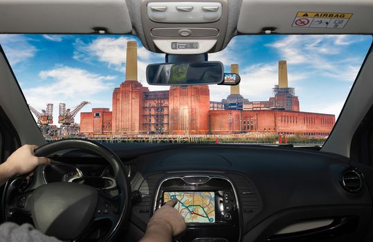 Driving a car while using the touch screen of a GPS navigation system towards Battersea Power Station, London, UK