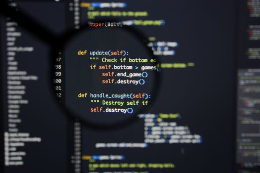 Real Python code developing screen. Programing workflow abstract algorithm concept. Lines of Python code visible under magnifying lens.