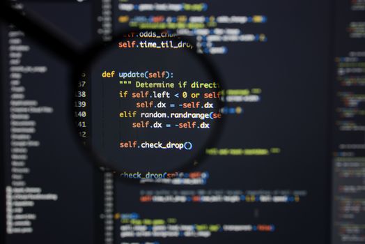 Real Python code developing screen. Programing workflow abstract algorithm concept. Lines of Python code visible under magnifying lens.
