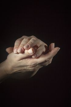 Female folded hands on a black background