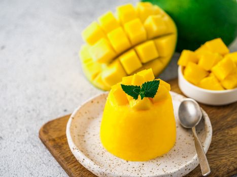 Mango Mousse on gray cement background with copy space left. Yellow mango mousse with sliced ripe mangoes