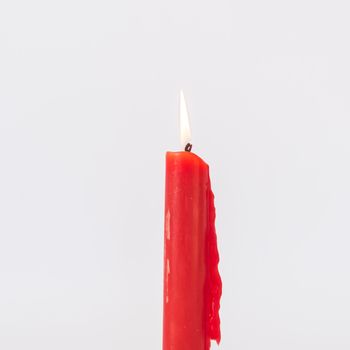 Close-up single red burning candle isolated on white background. Popular Asian stick candle for daily and holiday uses.
