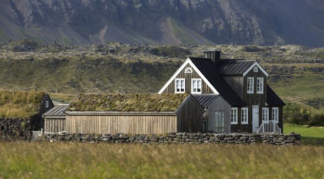 Lonely black wooden house at the bottom of mountain, Iceland.