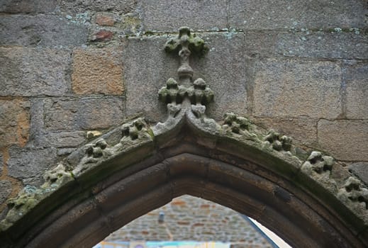Upper part of stone archway with cross on the middle