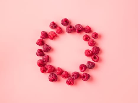 Creative layout with fresh ripe berries. Raspberry on pink background with round empty circle in center for copy space. Can use for your design. Top view or flat lay. Negative space for text