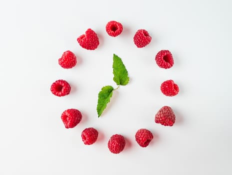 Clock made of berries leaves and raspberries. Isolated on white. Top view or flat lay. Health, vegetarian, detox, clean eating concept