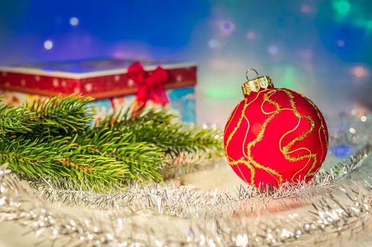 Red Christmas ball, fir branch, tinsel and with gift box
