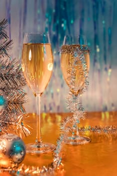 Glasses with wine, tinsel, Christmas tree and toys on the Golden surface