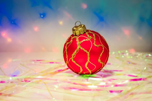 Red Christmas ball on the table with the tinsel on the background lights