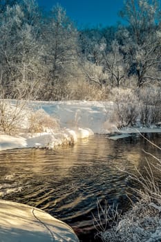 Winter sunny landscape with river and forest.