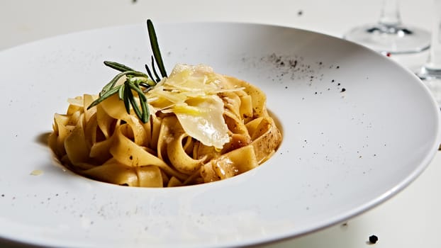 Close-up italian pasta plate with grated parmesan cheese and basil leaf.