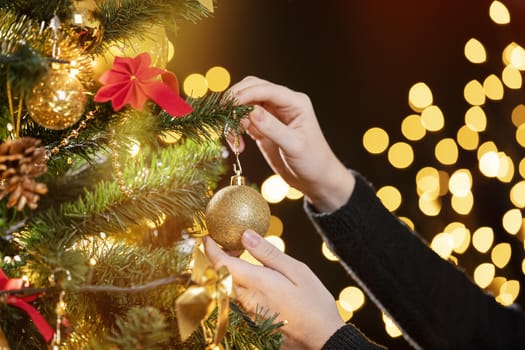 Girl decorates a Christmas tree. Closeup image of female hands decorating Christmas tree. Focus on her left hand!