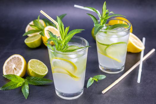 Homemade refreshing summer lemonade with mint in a glass on a grey and black background. Focus on leaf.