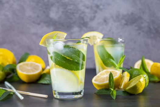 Cold refreshing summer lemonade with mint in a glass on a grey and black background. Focus on glass.