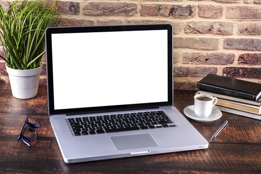 Laptop notebook with blank screen and cup of coffee and notepad pen and books on wooden table. 
Mock up on wooden table with laptop with blank screen, cup of coffee, pen, books and flower.
Focus on keyboard.