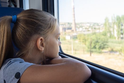 Teen girl looks out the window in an electric train