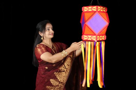 An Indian woman looking at the traditional Diwali lantern during Diwali festival in India, on the backdrop of Diwali fireworks.