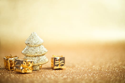 Christmas and New Year toy decorations fir tree and gift boxes on vibrant golden glitter background