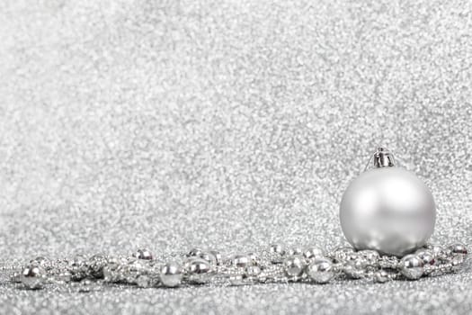 Christmas holiday composition of festive decor ball and beads on silver glitter bokeh background