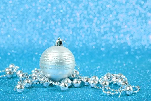 Decorative christmas ball and beads on blue glitter background