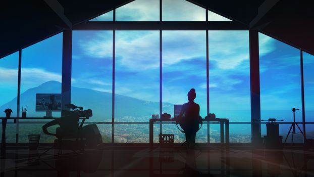 A female videographer works in a studio with panoramic windows overlooking a beautiful landscape.