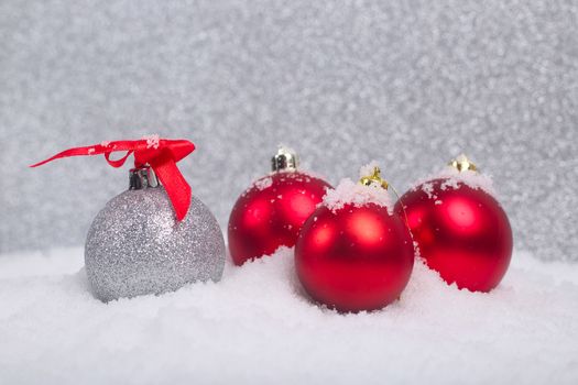 Red and silver christmas balls in snow on glitter background