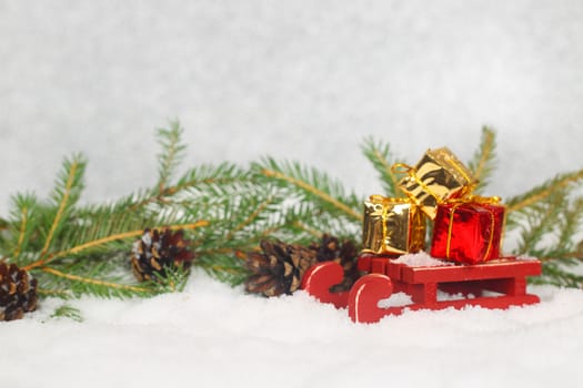 Christmas card with gifts on sledge standing on snow with fir branches