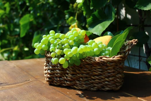 The picture shows a basket mit delicious fruits on wooden boards.