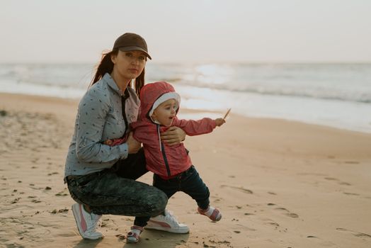 Mother and little daughter playing on the beach. Authentic image.