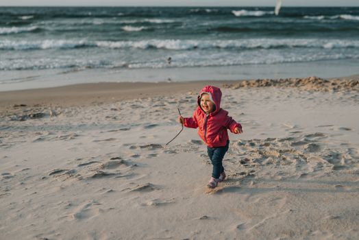 Adorable toddler girl on a sunny sand beach. Authentic childhood