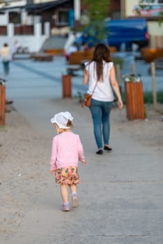 Happy mother and daughter in the park. Beauty nature scene with family outdoor lifestyle. Happy family resting together on the green grass, having fun outdoor. Happiness and harmony in family life.