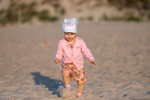Adorable toddler girl on a sunny sand beach. Authentic childhood