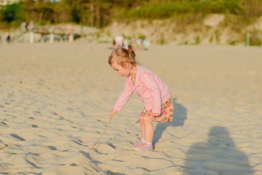 Adorable toddler girl on a sunny sand beach. Authentic childhood