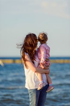 Mother and little daughter playing on the beach. Authentic image.
