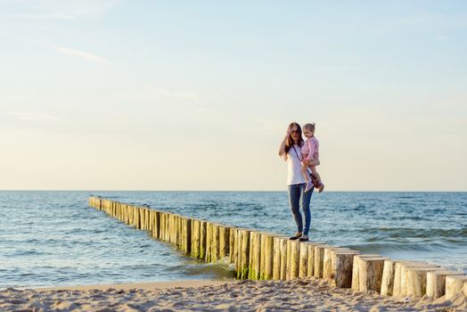 Mother and little daughter playing on the beach. Authentic image.