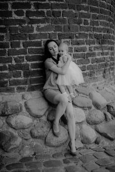 Happy mother and daughter in the park. Beauty nature scene with family outdoor lifestyle. Happy family resting together on the green grass, having fun outdoor. Happiness and harmony in family life.