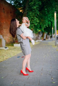 Happy mother and daughter in the park. Beauty nature scene with family outdoor lifestyle. Happy family resting together on the green grass, having fun outdoor. Happiness and harmony in family life.