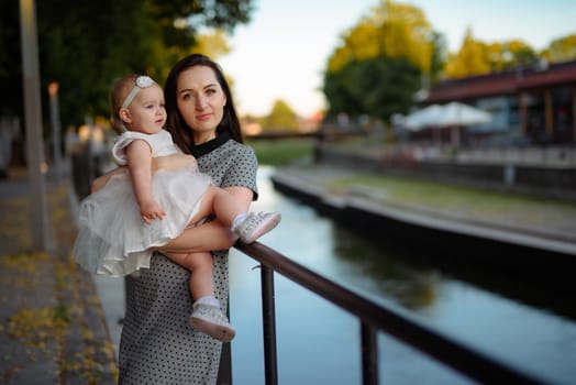 Happy mother and daughter in the park. Beauty nature scene with family outdoor lifestyle. Happy family resting together on the green grass, having fun outdoor. Happiness and harmony in family life.