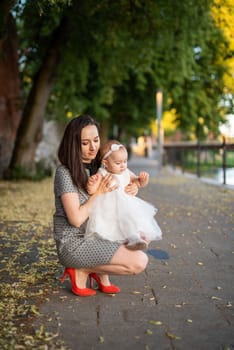 Happy mother and daughter in the park. Beauty nature scene with family outdoor lifestyle. Happy family resting together on the green grass, having fun outdoor. Happiness and harmony in family life.