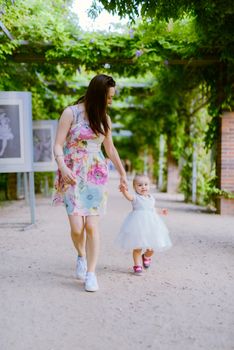 Happy mother and daughter in the park. Beauty nature scene with family outdoor lifestyle. Happy family resting together on the green grass, having fun outdoor. Happiness and harmony in family life.