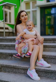 Happy mother and daughter in the park. Beauty nature scene with family outdoor lifestyle. Happy family resting together on the green grass, having fun outdoor. Happiness and harmony in family life.