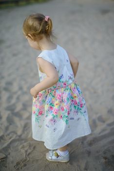 Adorable toddler girl on a sunny sand beach. Authentic childhood