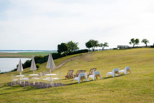 Empty beach chair on meadow on summer time. Sunlight and sea in the background. Coast line