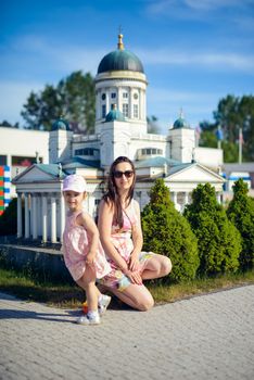 Happy mother and daughter in the park. Beauty nature scene with family outdoor lifestyle. Happy family resting together on the green grass, having fun outdoor. Happiness and harmony in family life.