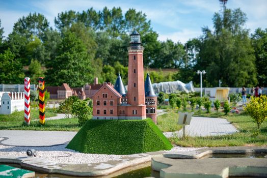 toy lighthouse, brick toy lighthouse and yellow sailboat with sand beach background