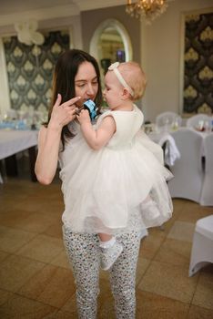 Baby girl 1 year old party time. Mother holding his baby girl on hand. Birthday party. Authentic childhood.